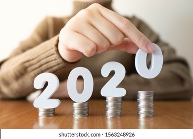 2020 New Year Saving Money And Financial Planning Concept. Female Hands Putting White Number 2020 On Stack Of Coins. Creative Idea For Business Growth, Tax Payment, Investment And Banking.