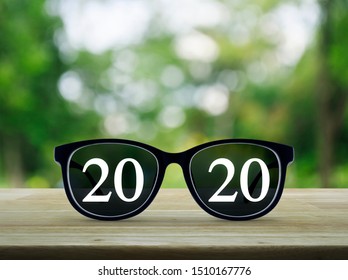 2020 White Text With Black Eye Glasses On Wooden Table Over Blur Green Tree In Park, Business Vision Happy New Year 2019 Concept