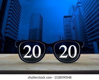 2020 White Text With Black Eye Glasses On Wooden Table Over Modern Office City Tower And Skyscraper, Business Vision Happy New Year 2020 Concept