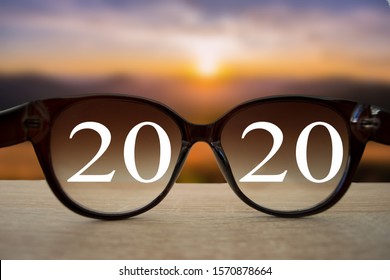 2020 white text with black eye glasses on wooden table over blur autumn landscapes. Business vision happy new year. - Shutterstock ID 1570878664