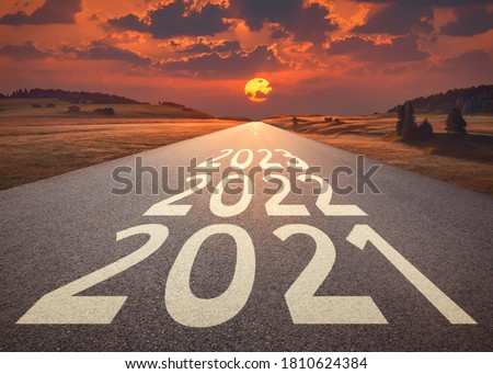 2021 2022 and 2023 new year written on highway as future and success concept against the happy looking sunset.