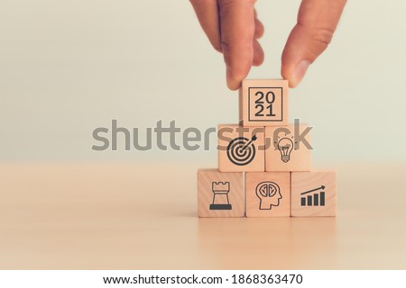 2021 concept business man hand arranging wood block . icon of business strategy including element with goal, idea, leadership, management of time, Knowledge, Initiative, Human relations in 2021 year