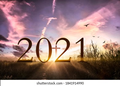 2021 concept: Wooden cross and 2021 against sunrise over grass