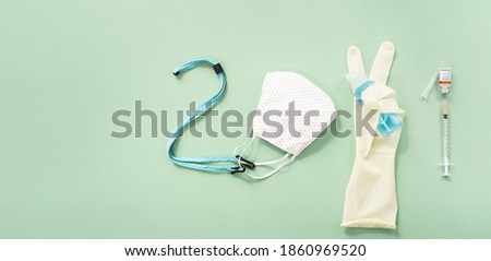 2021 eCard, New year holidays during Covid 19 pandemic concept. Flat lay of cloth face mask, protection glove, alcohol hand sanitizer and Vaccine vial with syringe arranging in 2021 shape. Health care
