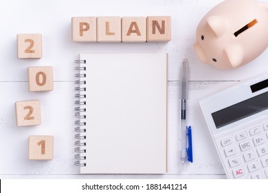 2021 Financial Plan Design Concept With Blank Notebook, Piggy Bank, Calculator And Wooden Block.