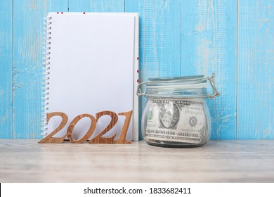 2021 New Year With Money Glass Jar And Wooden Number. Financial, Resolution, Goals, Plan And Saving Concept