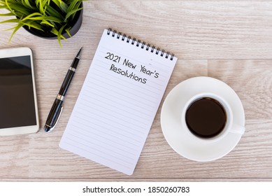 2021 New Year's Resolutions text on note pad with smart phone and cup of coffee