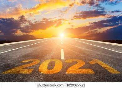 The 2021 numbers are written on a straight highway at sunset (sunrise). - Shutterstock ID 1829327921