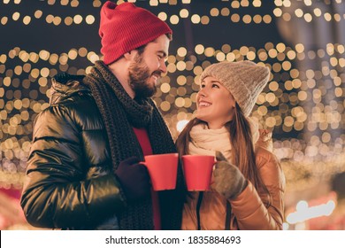 2021 X-mas Christmas Coming. Boyfriend Girlfriend Toast Cheers Eggnog, Beverage Mug Under Evening Outdoors Lights Wear Season Coat Scarf Hat