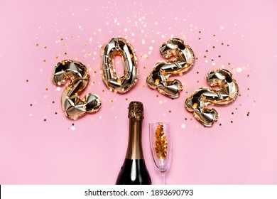 2022 golden foil balloons with champagne bottle and confetti. Happy new year and festive concept. Top horizontal view copyspace. 