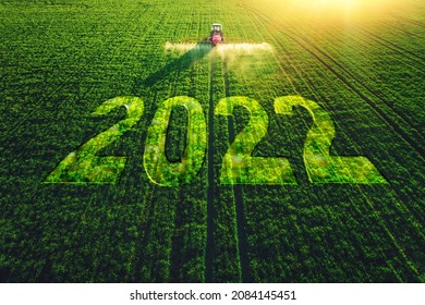 2022 Happy New Year concept and Aerial view of farming tractor plowing and spraying on field.