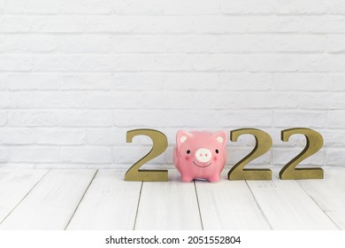 2022 new year and  piggy bank on white wood table over white background with copy space , saving concept