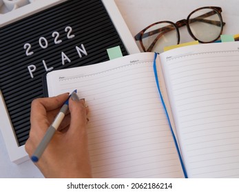 2022 New Year Resolution Office Concept On Yellow Desk With Notebook ,office Accessories And Money. Goal List 2021 With Change And Determination Concept. 2021 Budgeting.