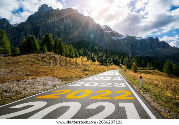 2022 New Year road trip travel and future vision
concept . Nature landscape with highway road leading forward to
happy new year celebration in the beginning of 2022 for fresh and
successful start .