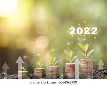 2022 new year Save money, success goals and investment growth concept. Stack coins on ground with white arrows rising on green nature background. Financial and business, Management money retire, tax.