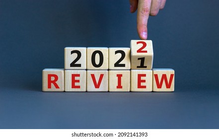 2022 review new year symbol. Businessman turns a wooden cube and changes words 'Review 2021' to 'Review 2022'. Beautiful grey background, copy space. Business, 2022 review new year concept.