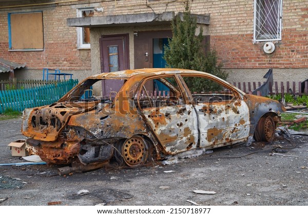 2022 Russian invasion of Ukraine war torn city\
destroyed car burn out. Russia war damage building destruction city\
war ruins city damage car. Disaster area. cars beaten by shrapnel\
and burnt