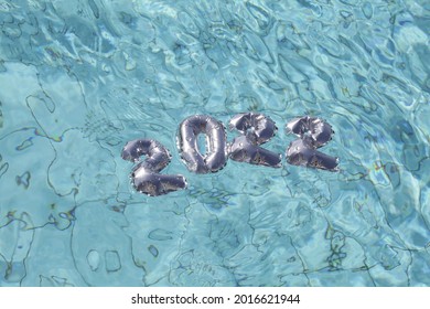 2022 silver balloons floating in blue water in pool. Christmas and happy new year concept.
