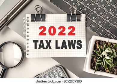 2022 TAX LAWS Text On A Notepad And Laptop, Office Tools. Business, Financial Concept. Remote Training. Coffee Break, Ideas, Notes, Goals Or Writing A Plan, Invitation Concept. Top View, Flat Lay.