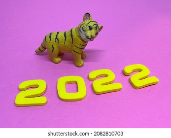 2022 is the year of the tiger. A tiger and  yellow numbers on the pink background.New year's concept.Chinese Zodiac Sign Year of Tiger, Happy Chinese New Year, Year of the Tiger. 