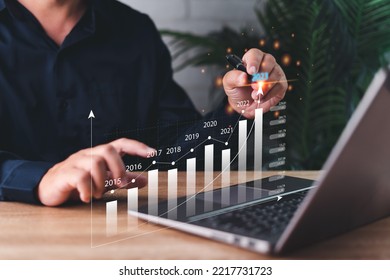 2023 business finance technology and investment concept, businessman pointing on graph development to success and growing, analyzing financial graph on virtual screen.and laptop on table