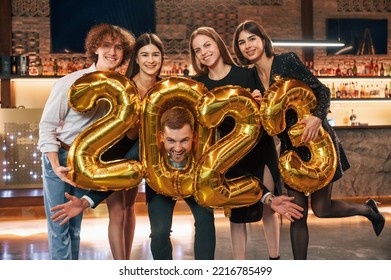 2023 is coming. With balloons. Group of people in beautiful elegant clothes are celebrating New Year indoors together. - Shutterstock ID 2216785499
