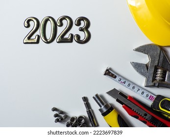 2023 with construction tools, yellow hard hat on white background with copy space. New Year and Christmas construction greeting card. For advertising or web design. Repair home at Christmas. Flat lay.