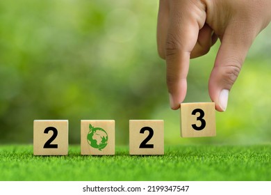 2023. Enviromental Sustainability Target. Hand Puts Wooden Cubes With Number 3 Icons With 2023 Icons On Green Background. Green Community. Goals,plan,opportunity, New Green Business And Social.