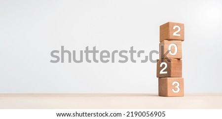 2023 Happy New year background banner. Two thousand Twenty-Three year numbers on wooden cube blocks stack on white background with copy space. Welcome, Merry Christmas, and Happy New Year in 2023.