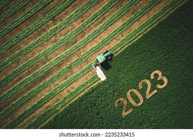 2023 Happy New year concept for agriculture, business, goals, success and new start banner. Industrial tractor on a green field. - Shutterstock ID 2235233415