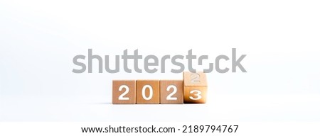 2023 happy new year concept banner. Flipping the 2022 to 2023 year numbers calendar on wooden cube blocks isolated on white background for new year change for starting new things or new business.