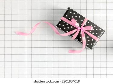 2023 New Year Minimal Concept With Polka Dot Wrapping Paper Gift Box With Pink Ribbon Bow On Grid Background. Christmas Celebration, Birthday, Women's Day Aesthetic. Shopping, Party, Holiday Idea.