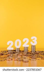 2023 New year saving money and financial planning concept. Stack of coins with number 2023 on wood table over gold background. Creative idea for business growth, investment, profit and banking. - Shutterstock ID 2237851067