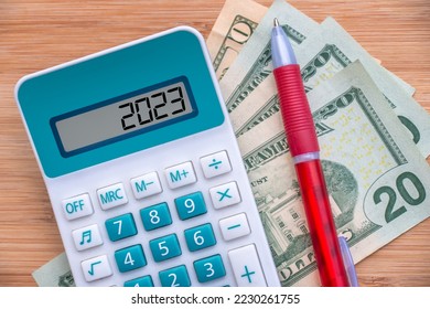 2023 numbers on a calculator and dollars banknotes, new year finance, money inflation and budget illustration