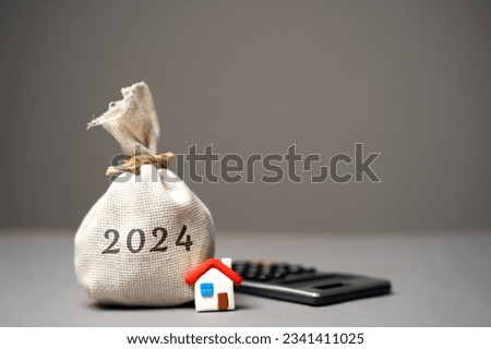 2024 budget real estate concept. Family budget planning. Investments, plans, savings. Mortgage and mortgage rates. Forecasts. Loan. Refinance home. Money bag and miniature house.