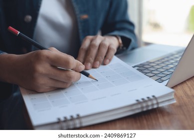 2024 Event planner timetable agenda plan on schedule event. Business woman checking planner, taking note on calendar desk on office table. Calendar event plan, work planning