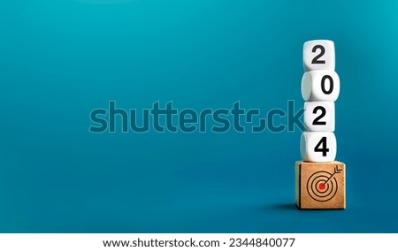 2024 Happy New year background banner. Numbers on white dices on target icon on wooden cube blocks stacked on blue background with copy space. Welcome, Merry Christmas, and Happy New Year in 2024.
