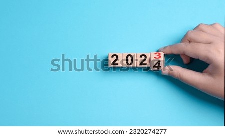 2024 Happy New Year eve wooden blocks flip change hand blue background. Countdown starting ending 2023 action schedule calendar strategy future vision. Business startup plan resolution celebration