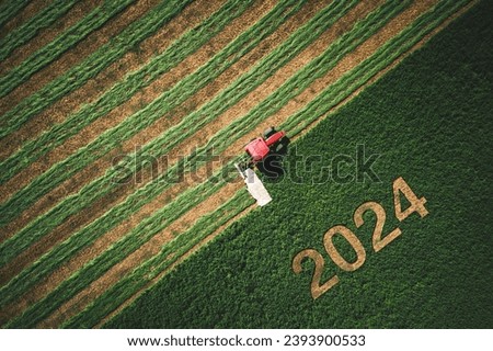 2024 Happy Ney Wear concept and red tractor mowing green field. Foto d'archivio © 