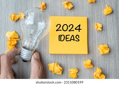 2024 Idea words on yellow note and crumbled paper with Businessman holding lightbulb on wooden table background. New Year New Start Creative, Innovation, Imagination, Resolution and Goal concept - Shutterstock ID 2311080199