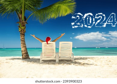 2024 new year concept with woman in santa's hat  relaxing on tropical beach. - Shutterstock ID 2393900323