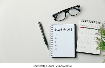 2024 New Year goal, plan, and action concepts. 2024 goals Text on Note Pad with calendar, glasses on the table.New Year's resolutions plan.Happy New Year theme, top view, copy space.
