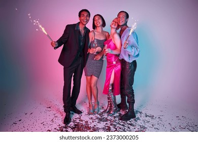 2024 New Year party, positive multiethnic friends holding sparklers and champagne on purple pink - Shutterstock ID 2373000205