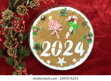 2024 New Year's cake and artificial christmas decorations on red background
