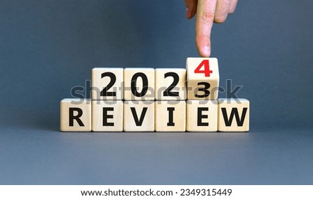 2024 review new year symbol. Businessman turns a wooden cube and changes words Review 2023 to Review 2024. Beautiful grey background, copy space. Business 2024 review new year concept.