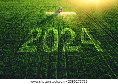 2024Happy New Year concept and Aerial view of farming tractor plowing and spraying on field.