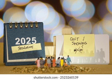 2025 calendar with a sticky note labeled "Resolutions" and another note with the message "quit smoking" on a card. Small figurines of people stand in front of the display - Powered by Shutterstock