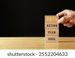 2025 GOAL PLAN ACTION. start up business. new year. Put last piece of wooden cube with the letters 2025. Steps required to achieve the goal