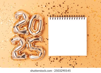 2025 New Year wish list concept. Empty notepad mockup, shiny stars confetti and golden numbers foil balloons.