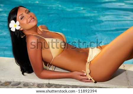 20-25 years woman portrait relaxing close to swimming pool at exotic surrounding